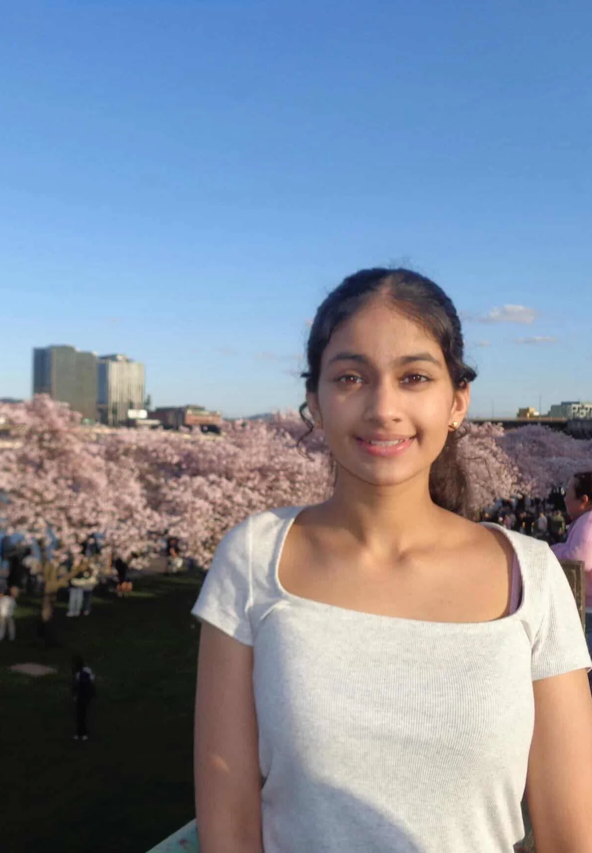 Anisha, smiling, in front of cherry blossoms in Portland