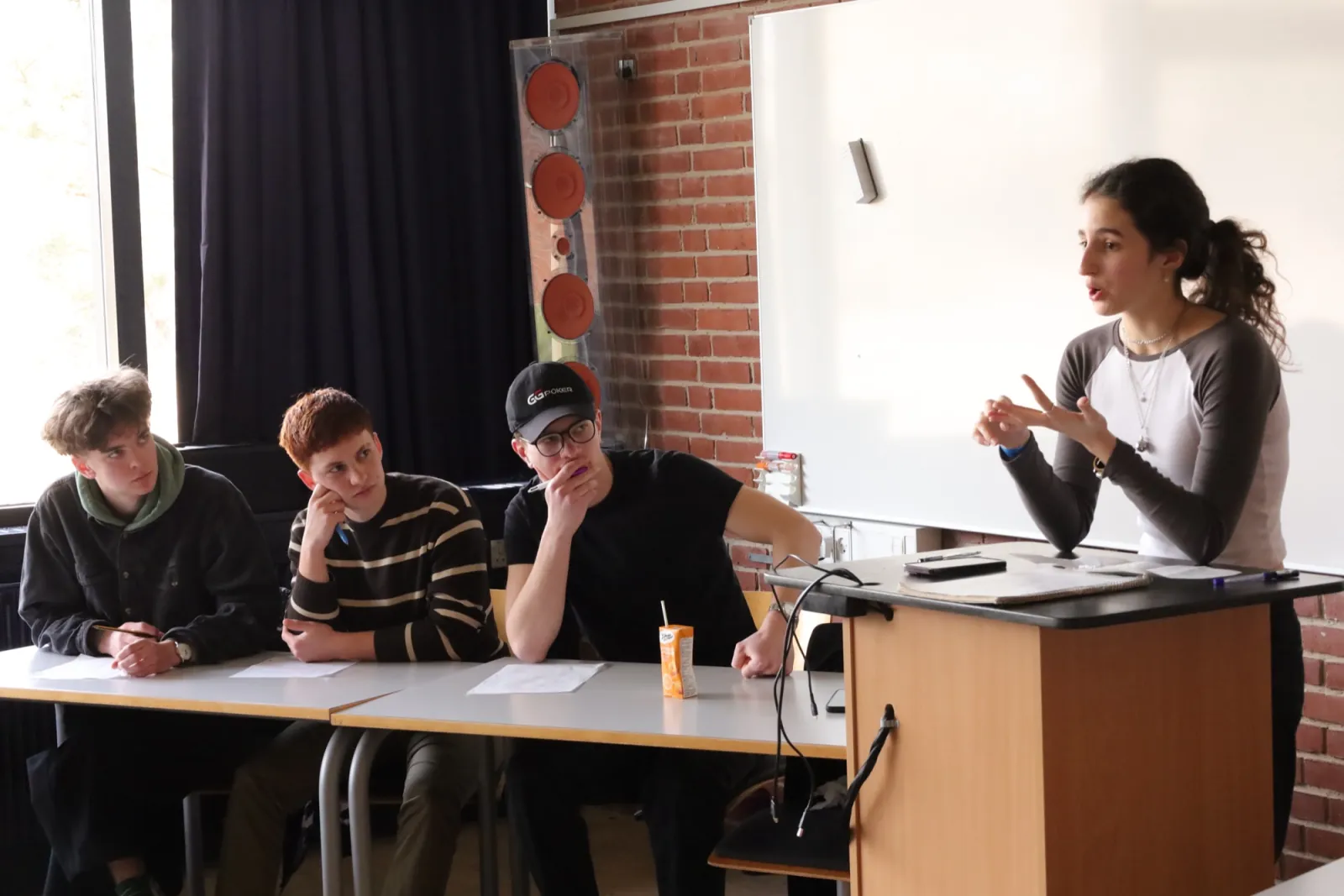 A student explaining her work to three others at a classroom table