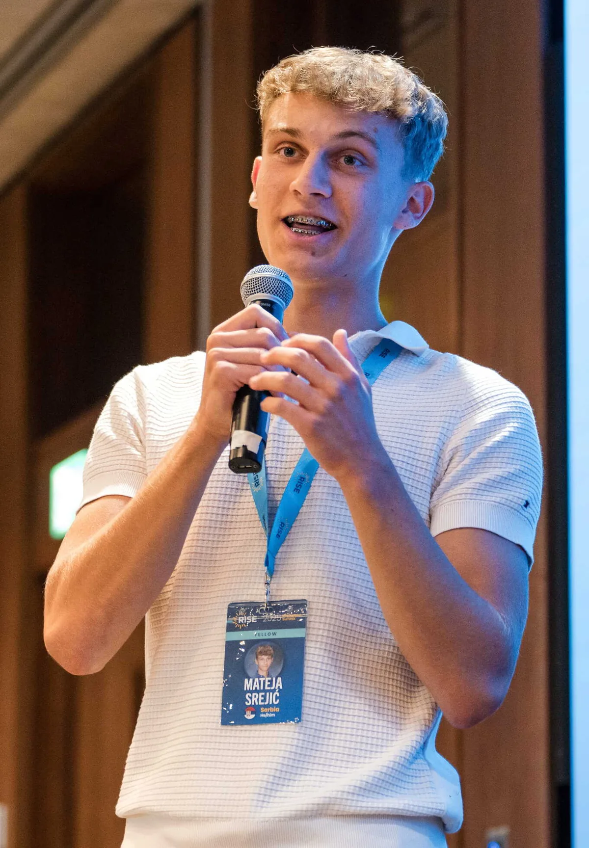 Mateja speaking into a microphone on a conference stage