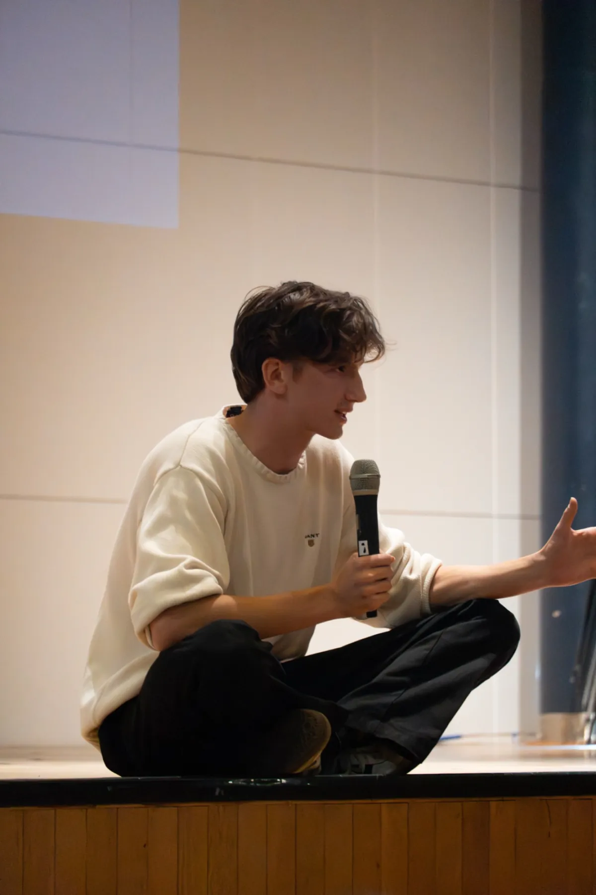 Matyas Supka sitting on a stage, talking to an audience
