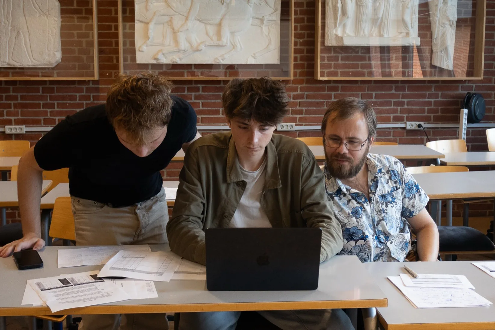 Morris working on a laptop at a table with two others